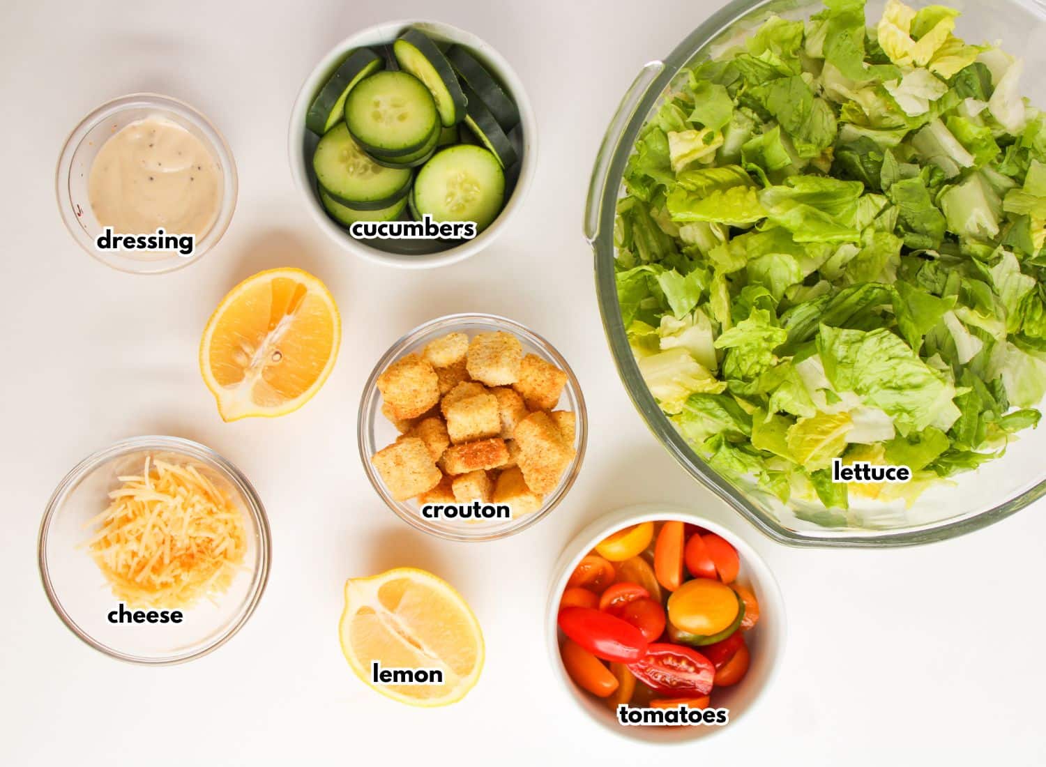 Bowls of salad ingredients on a counter labelled with text.