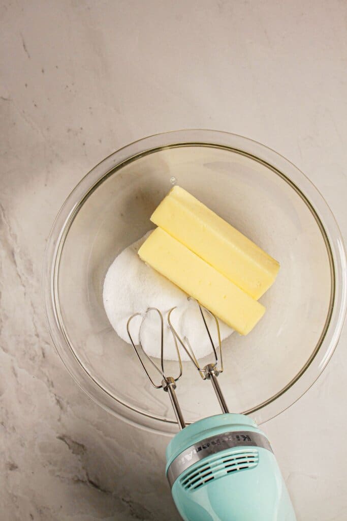 Butter and sugar in a glass mixing bowl.