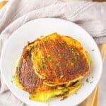 Parmesan cabbage steaks stacked on a white plate.