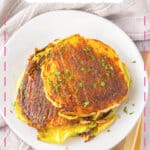 Parmesan cabbage steaks stacked on a white plate.