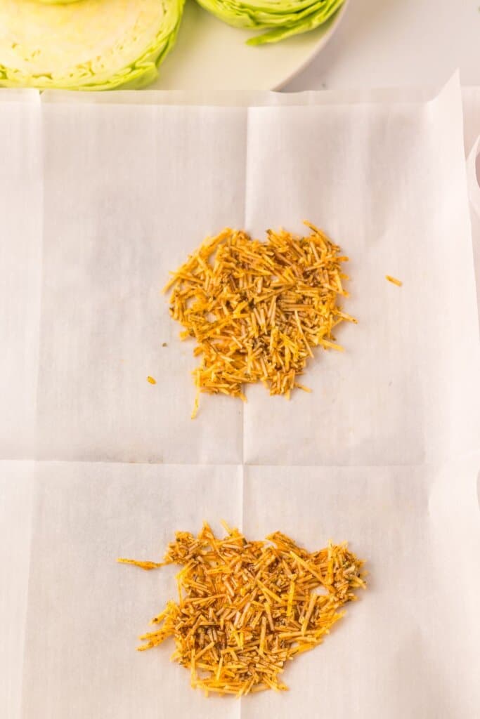Cheese and oil mixture being sprinkled on parchment paper.
