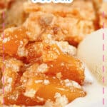 Small plate full of peach cream cheese dump cake with a top of vanilla ice cream.