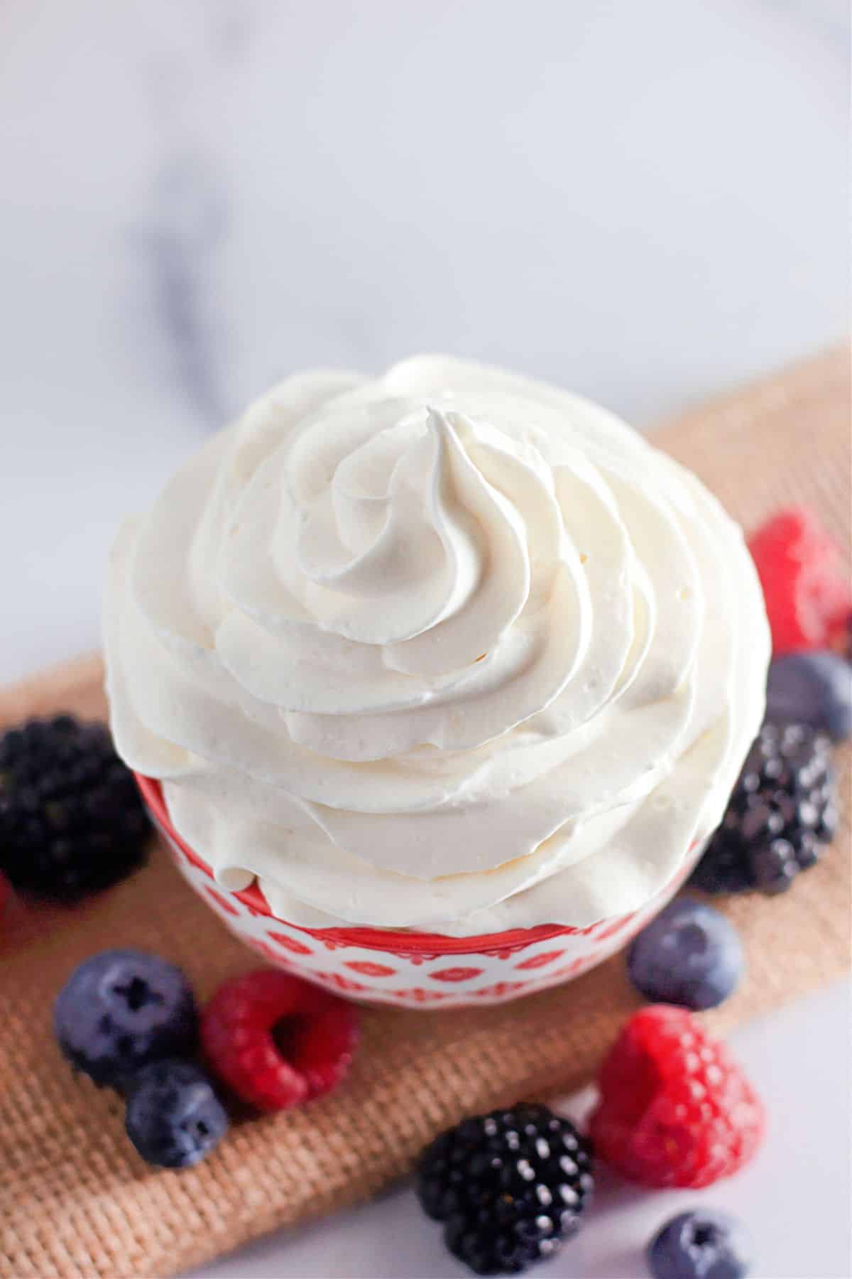 Red and white bowl full of stabilized whipped cream.