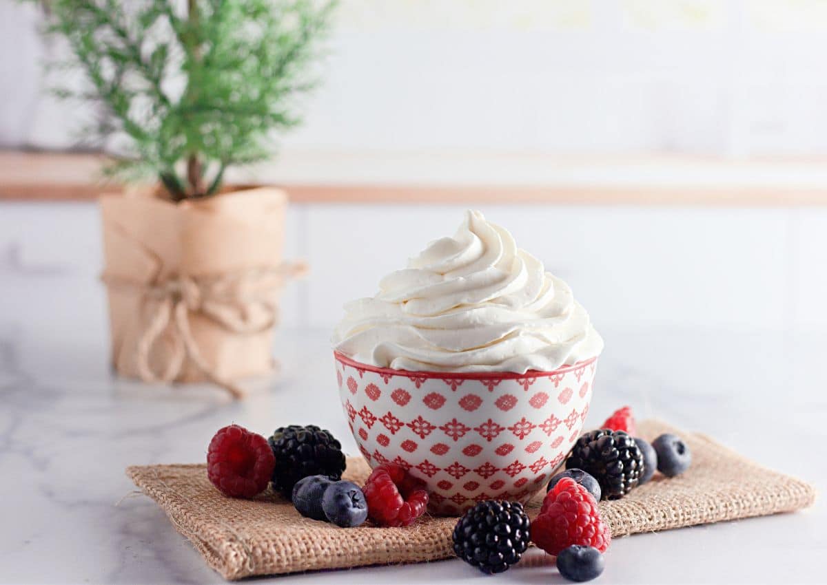 Red and white bowl full of stabilized whipped cream.