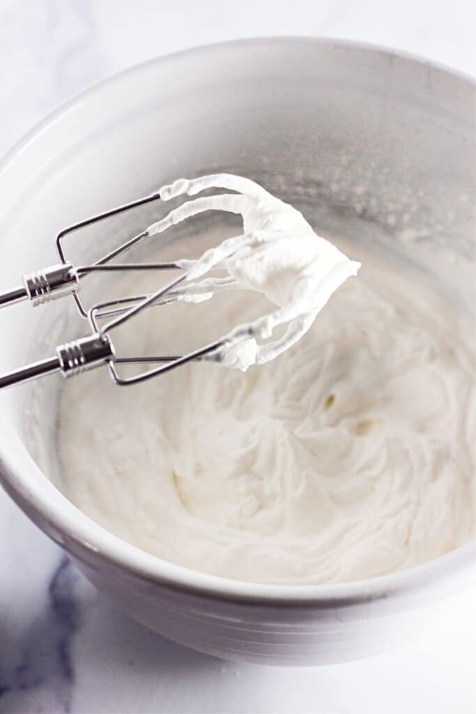 Stabilized whipped cream in a large mixing bowl.
