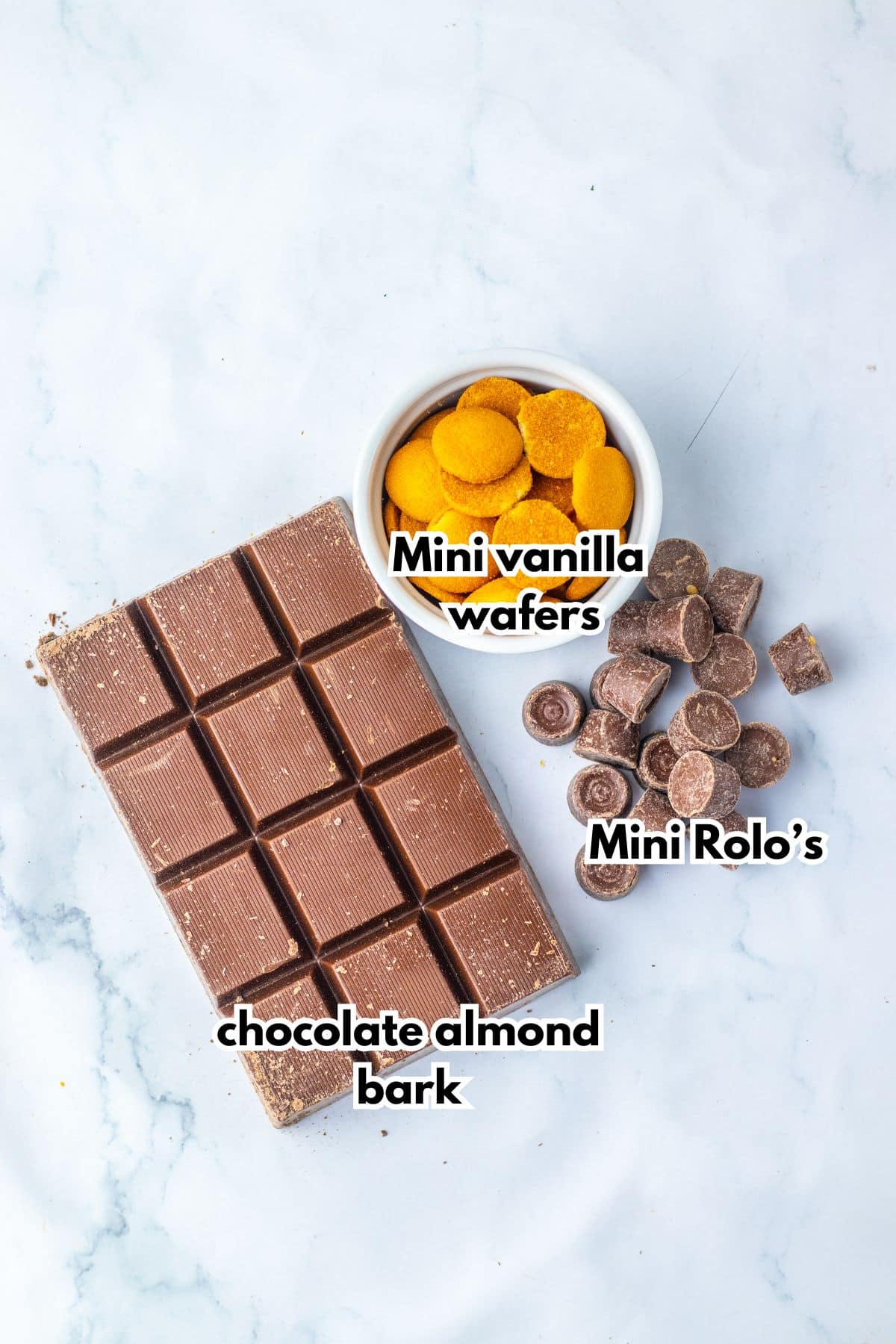 Bowl of vanilla wafers, Rolo's and chocolate almond bark on a counter.
