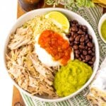 Rice, meat, beans, salsa, guacamole, and sour cream in a white bowl.