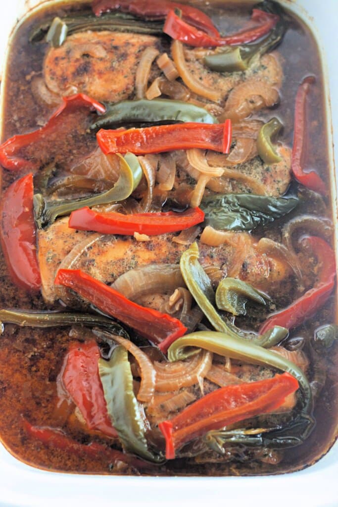 Chicken breasts, peppers, and onions in a slow cooker.