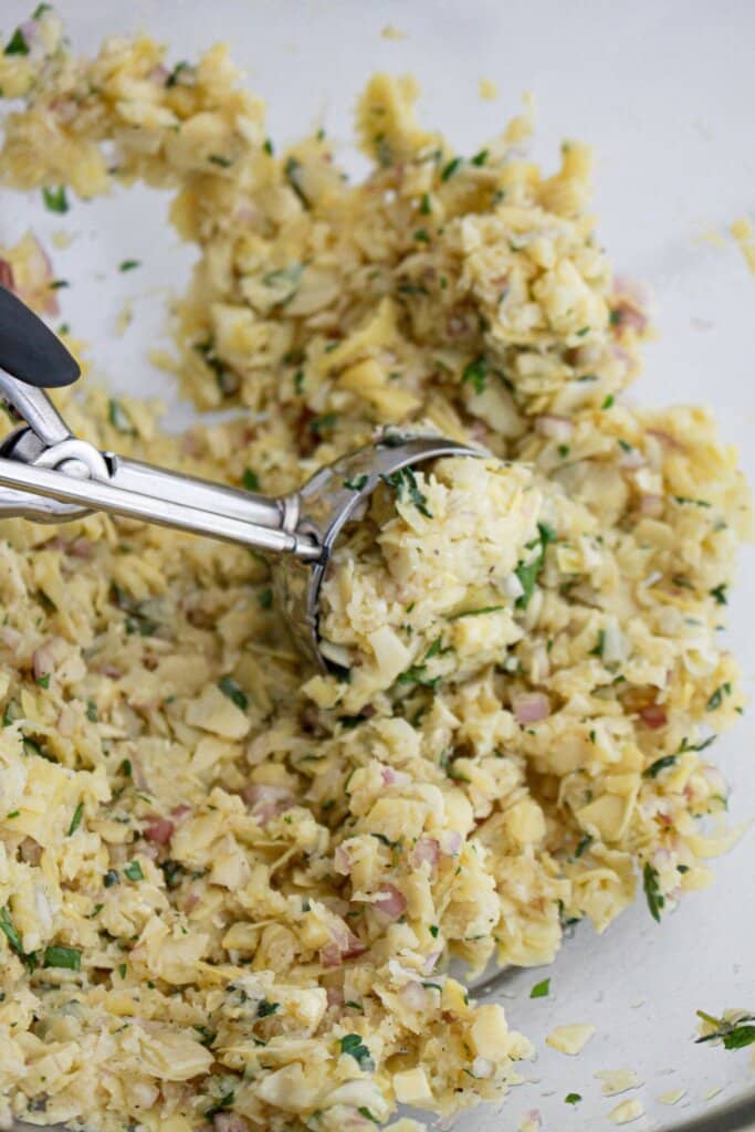 Meatballs being shaped with a cookie scoop.