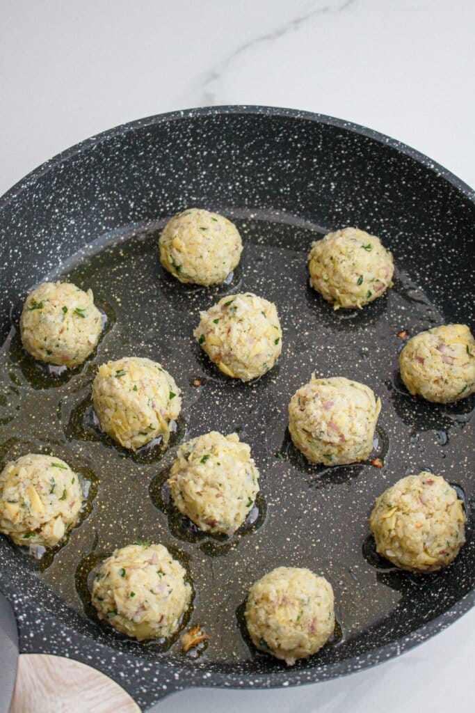 Meatballs being cooked in a skillet.