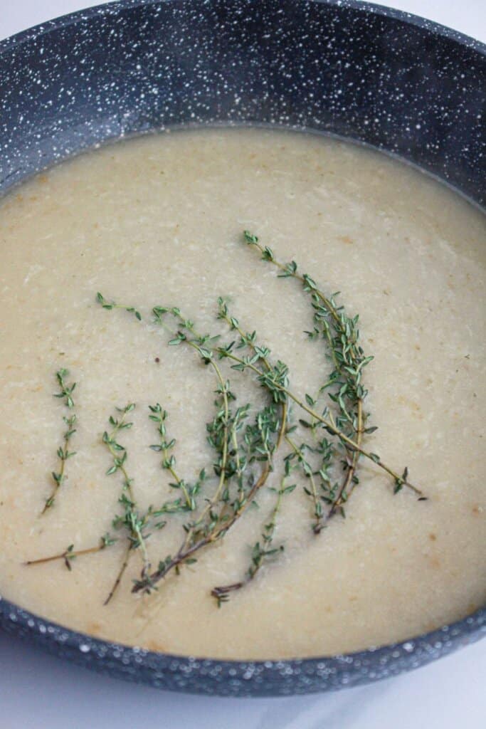 Broth and herbs being added to a skillet.
