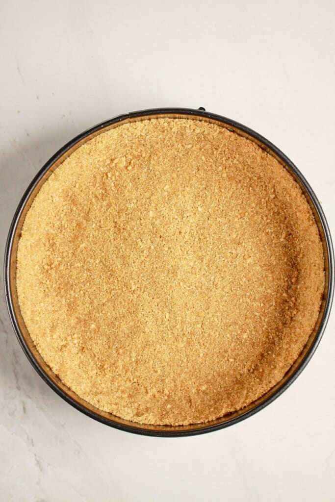 Crust being pressed into a springform pan.