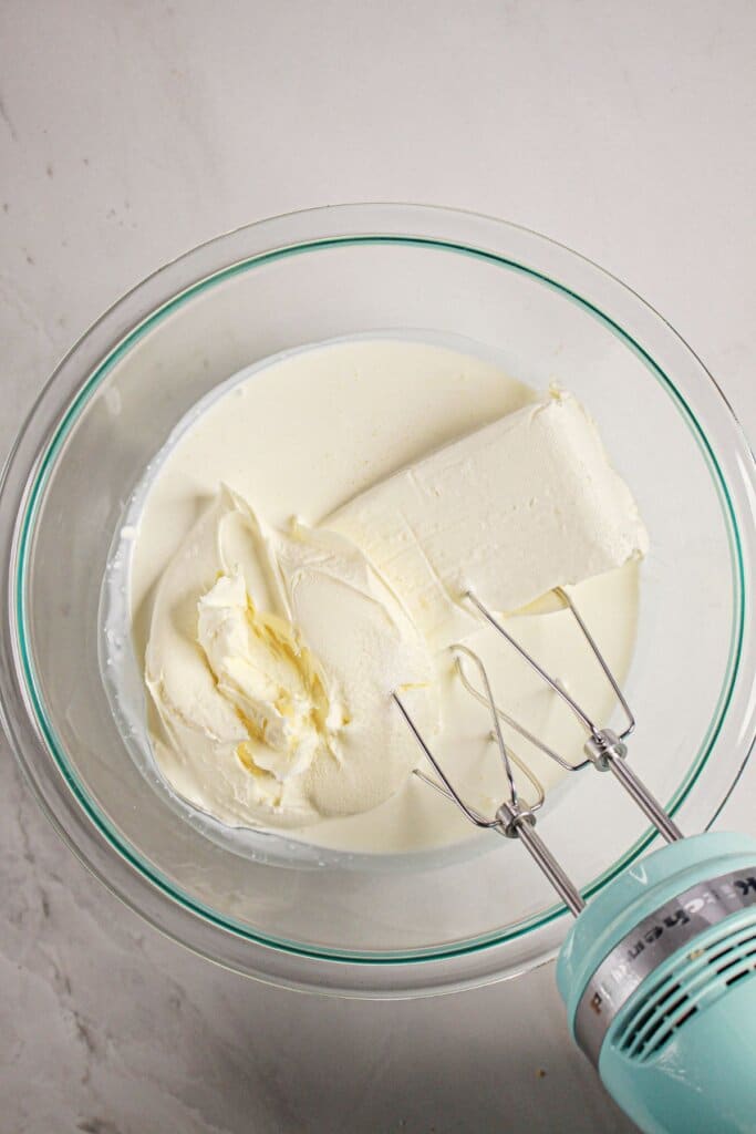 Cream cheese, and mascarpone cheese being mixed together.