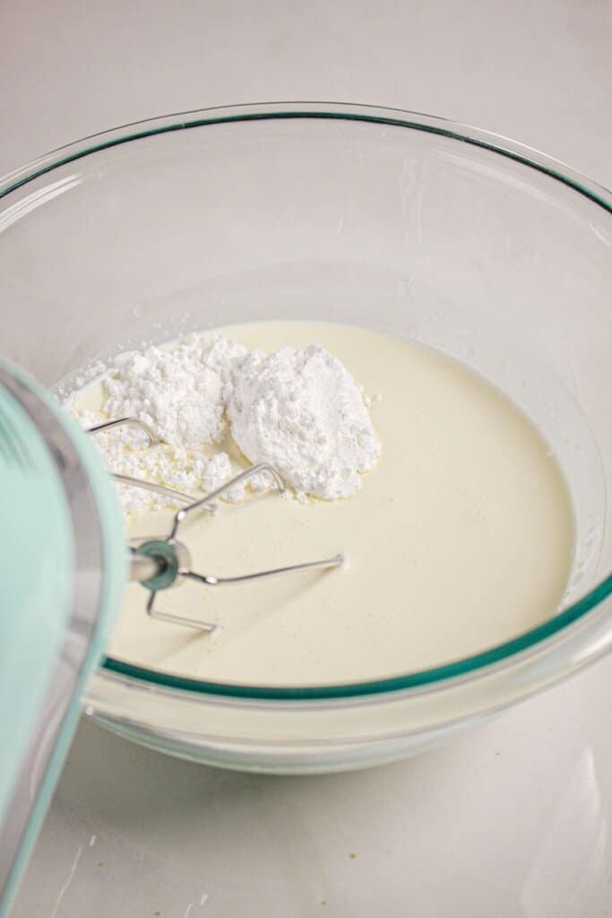 Heavy cream being whipped in a glass bowl.
