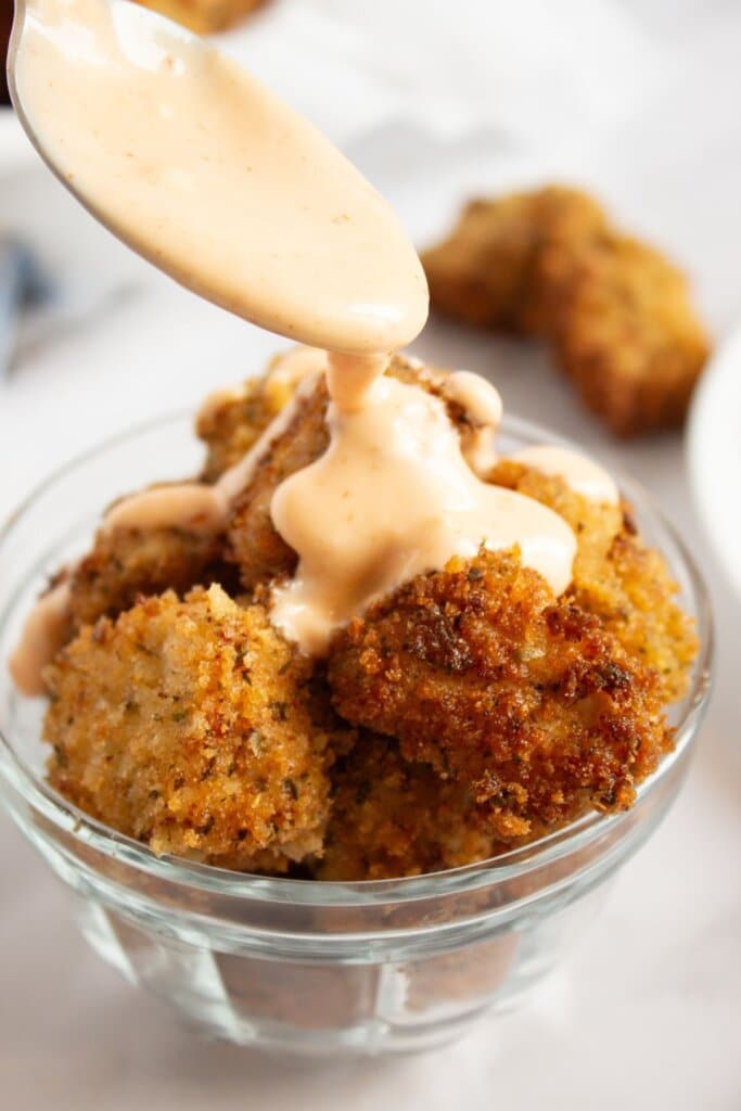 Sauce being poured over nuggets.