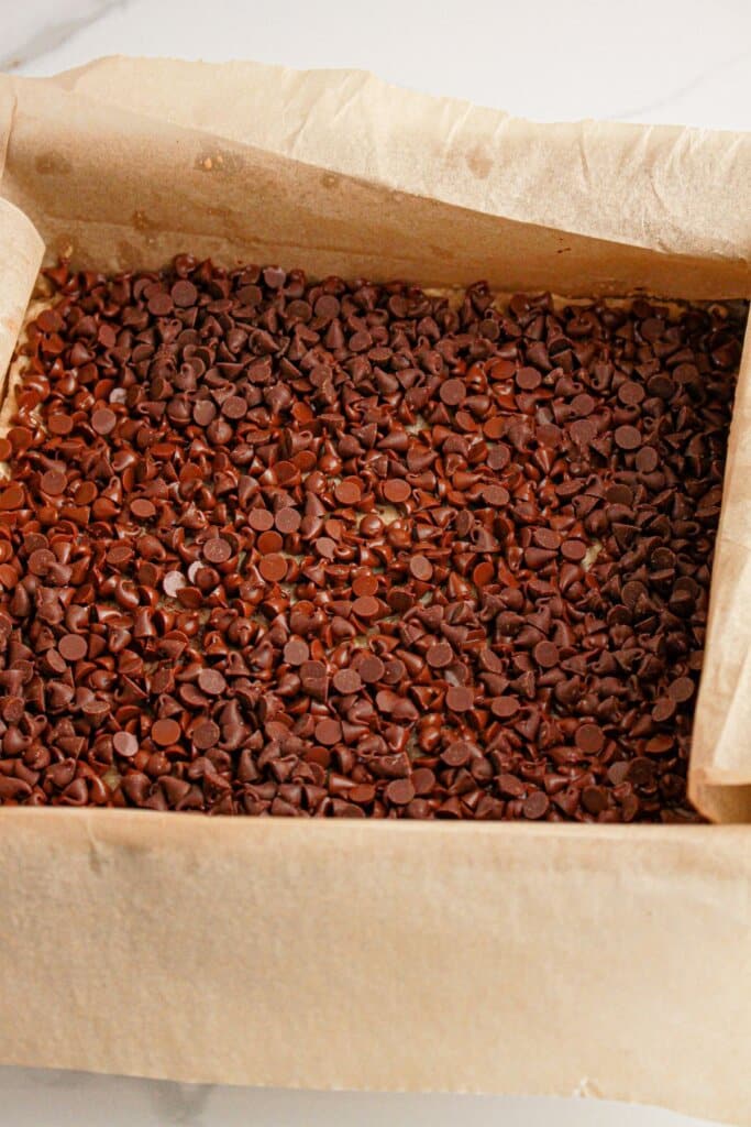 Chocolate chips on top of crust in a baking dish.