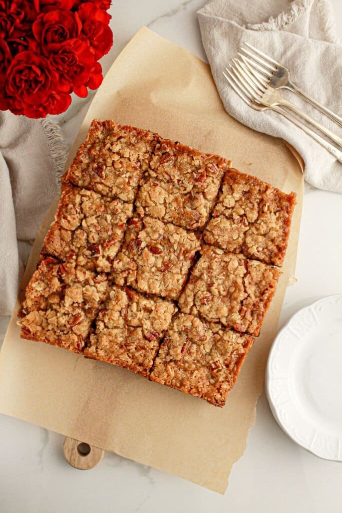 Dessert being sliced into squares on parchment paper.