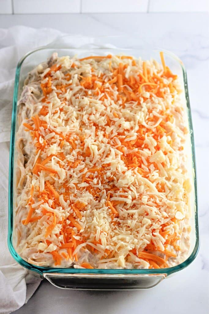 Cheese on top of casserole in a glass baking dish.