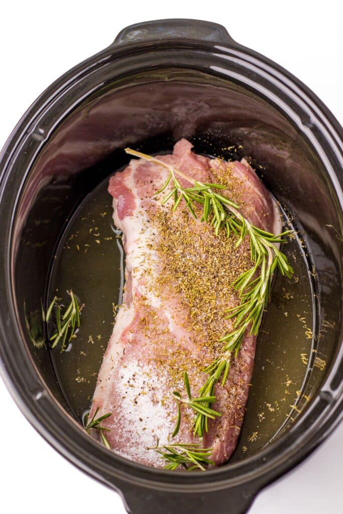 Pork loin and herbs in a slow cooker.