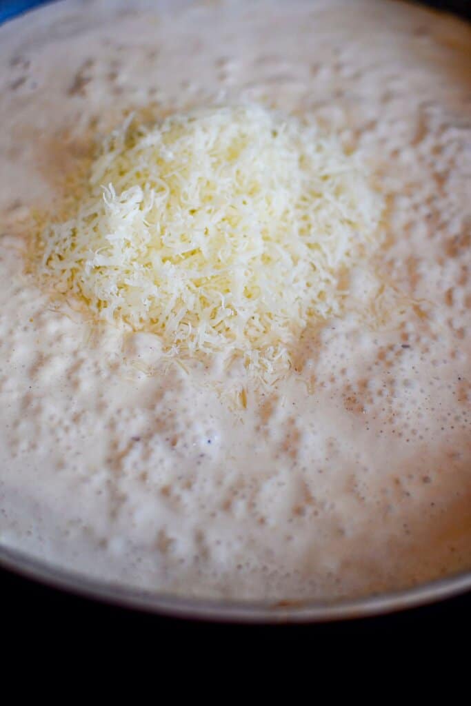 Parmesan cheese being added to a skillet.