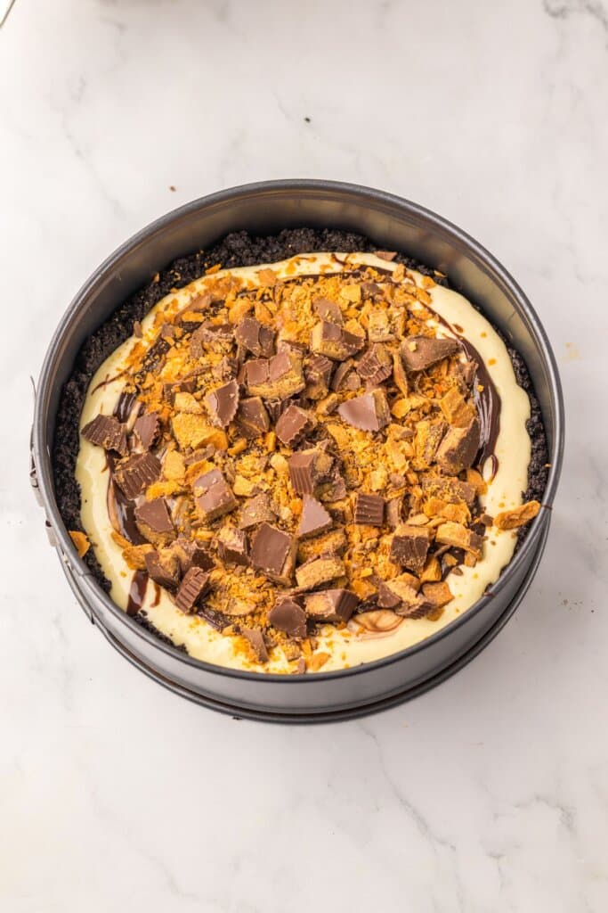 Candy being added to the top of cheesecake.