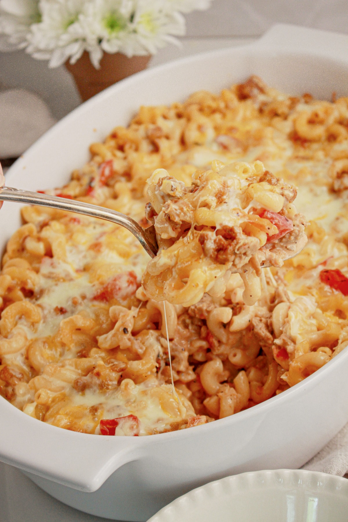 Spoonful of hamburger noodle casserole above the baking dish.