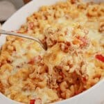 Spoonful of noodle casserole held above the baking dish.