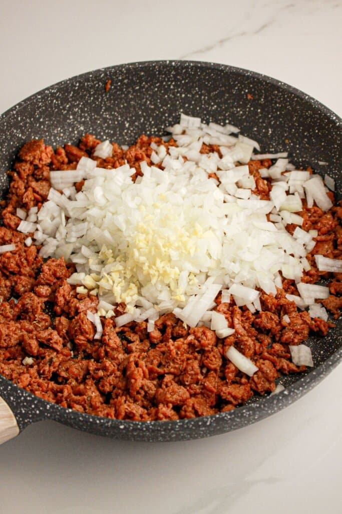 Ground beef, onions, and garlic being cooked in a skillet.
