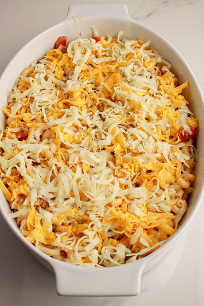 Cheese being sprinkled on top of baking dish.