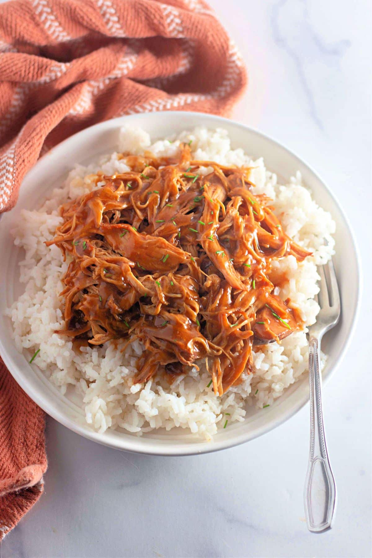 Shredded honey garlic chicken on top of a bed of rice.