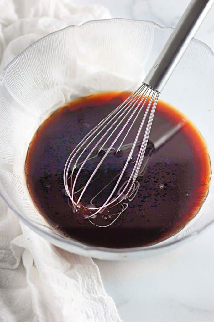 Sauce being mixed with a whisk in a glass bowl.