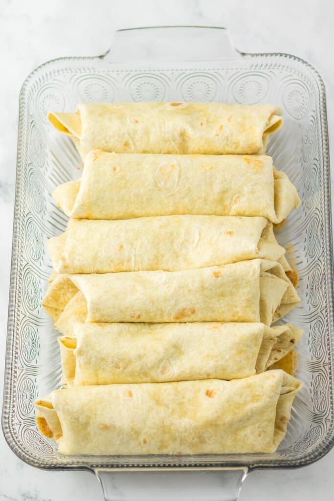 Rolled tortillas in a glass baking dish.