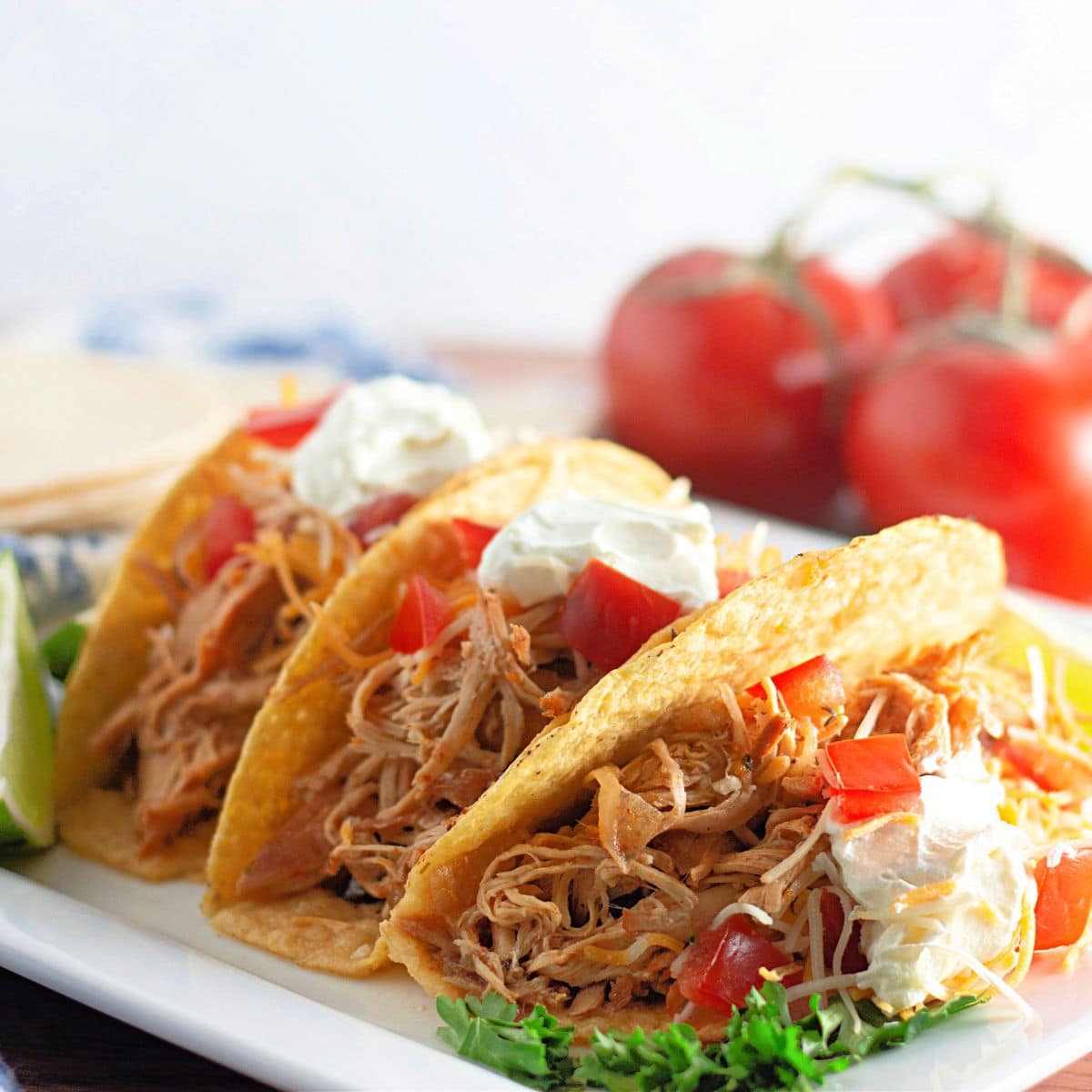 Three Mexican shredded chicken tacos on a plate.
