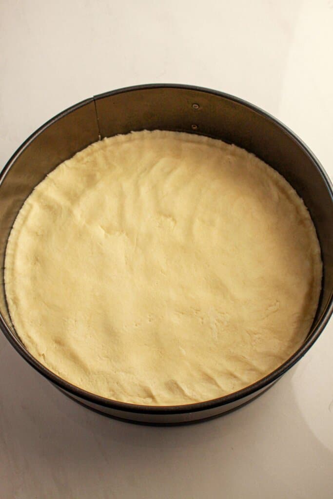 Crust being pressed into a springform pan.