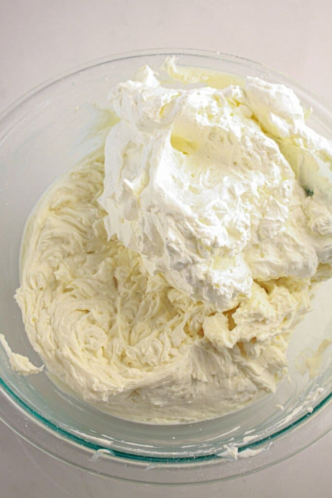 Whipped cream being added to cream cheese.