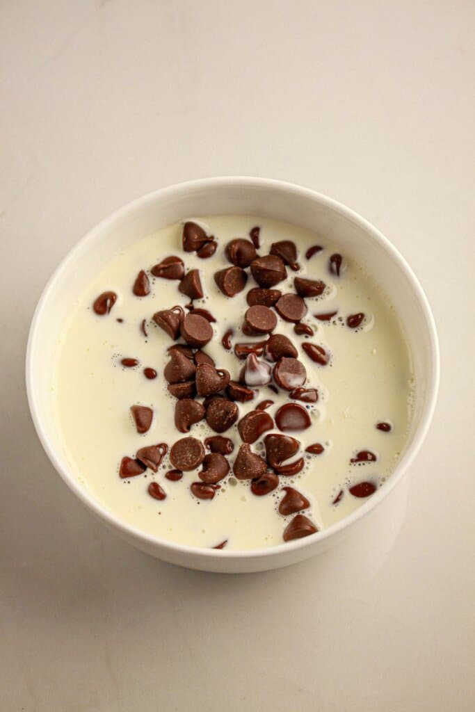 Chocolate chips and evaporated milk in a bowl.