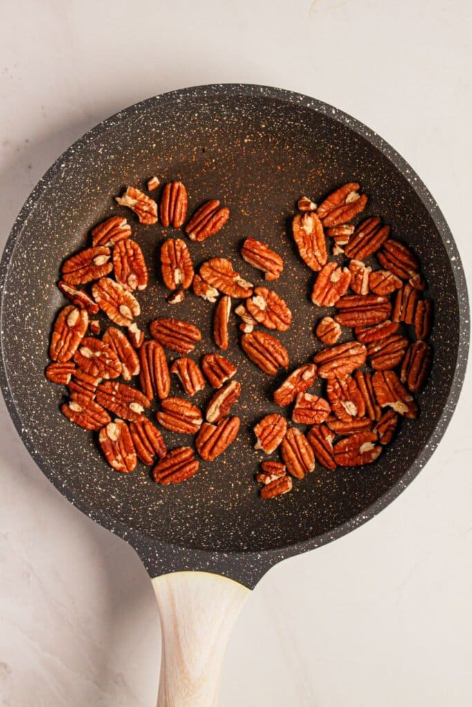 Pecans being tossed in a skillet.