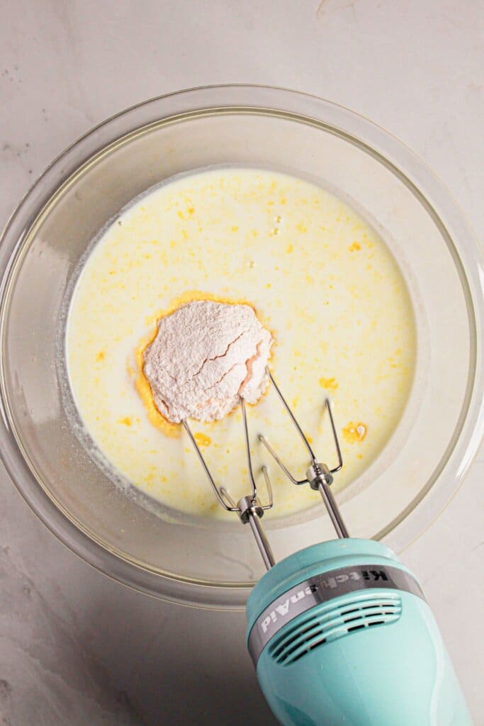 Pudding mix and milk being mixed in a glass bowl.