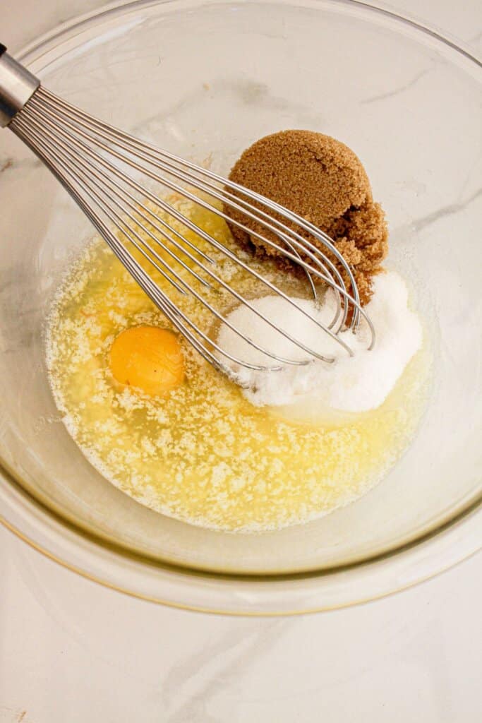 Butter, eggs, and sugar being mixed in a glass mixing bowl.