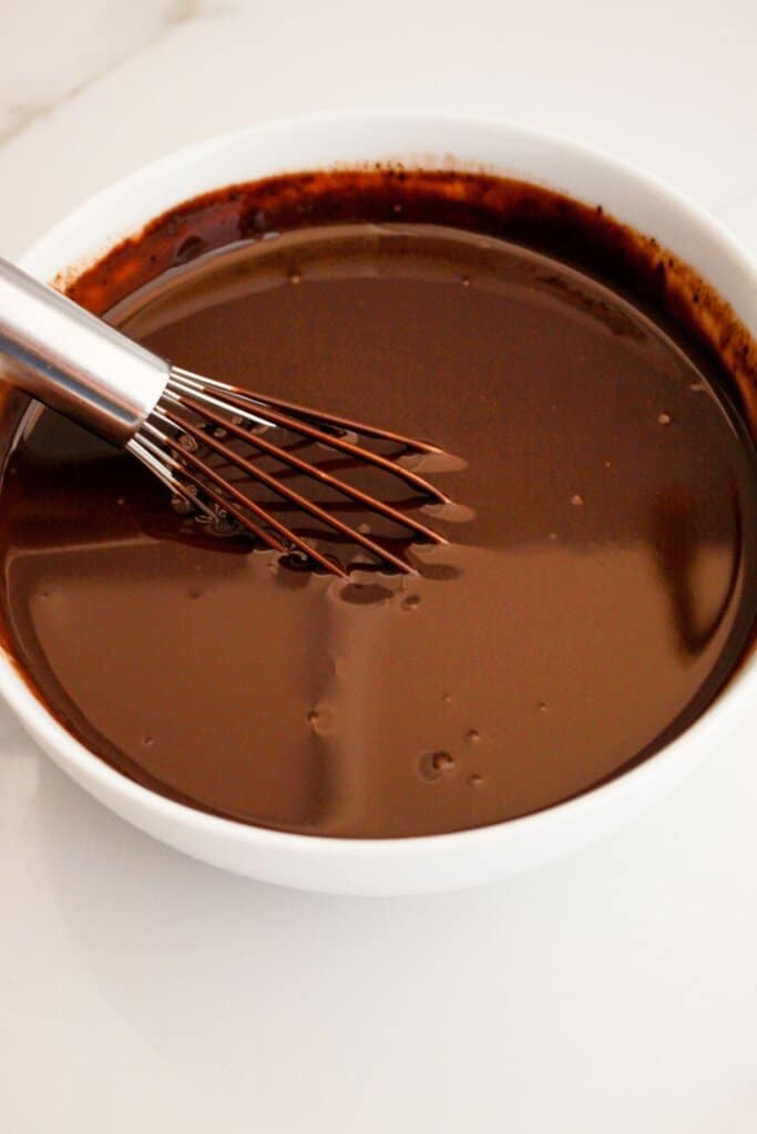 Chocolate ganache being mixed in a bowl.