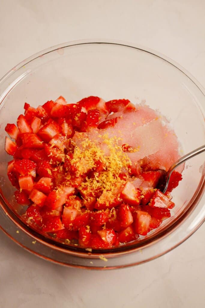 Strawberries being mixed with sugar and zest.