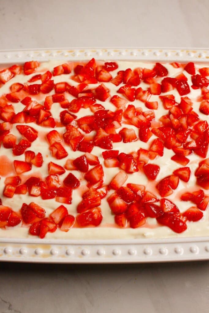 Strawberries being added to the top of a cake.