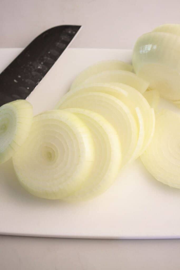 Onions being sliced on a cutting board.