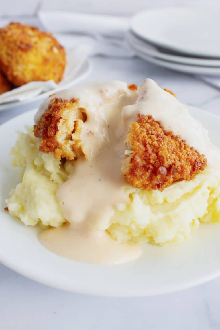 Mashed potatoes on a plate topped with chicken patty.