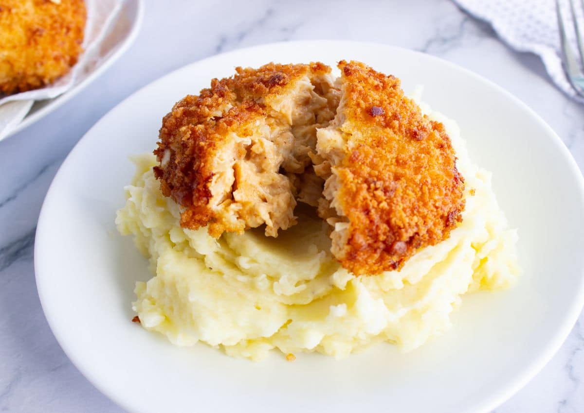 Mashed potatoes on a plate topped with chicken patty.