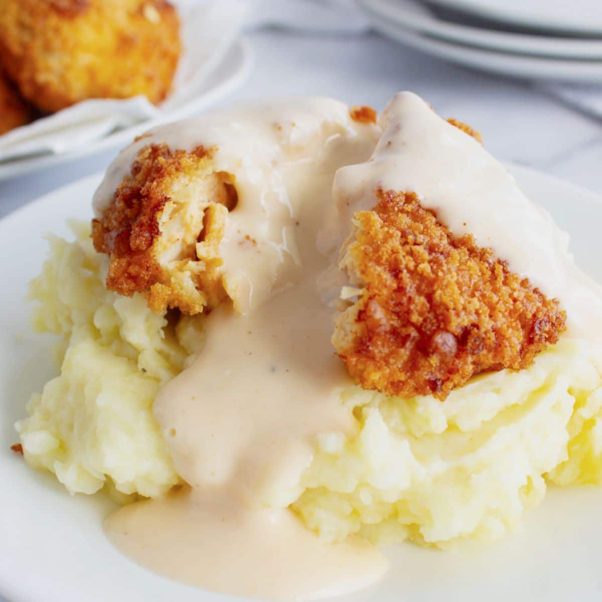 Mashed potatoes on a plate topped with chicken patty.