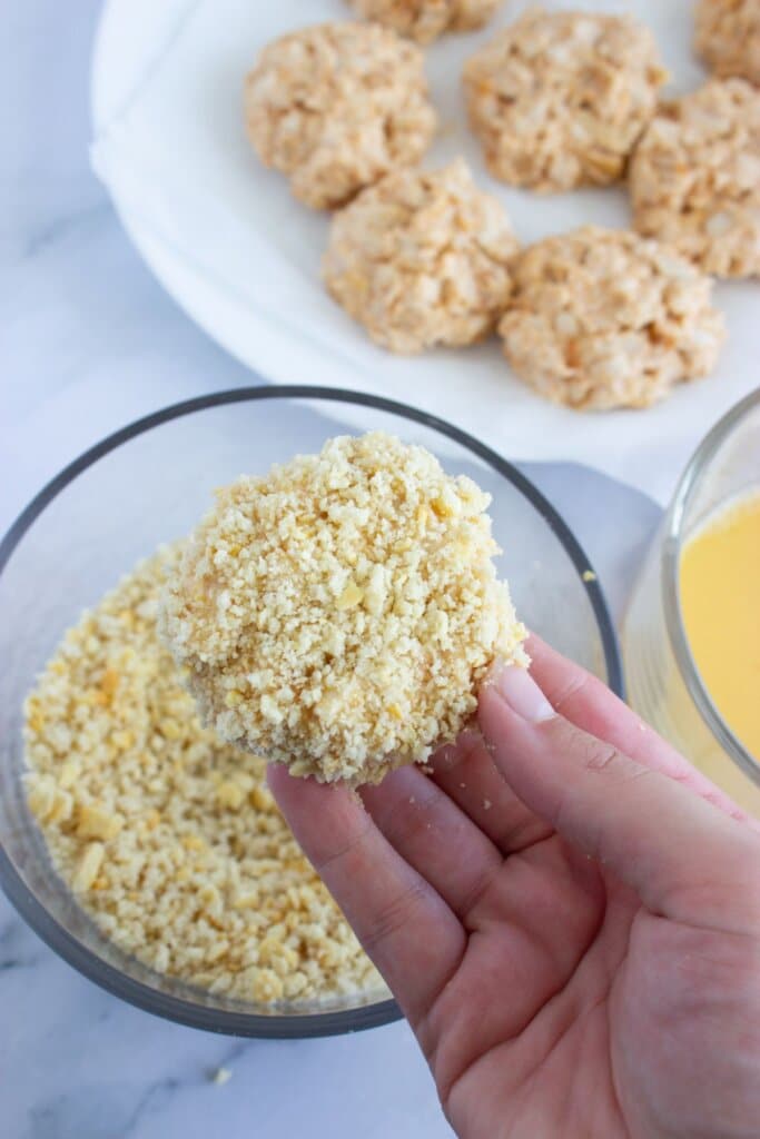 Croquette being breaded in bread crumbs.
