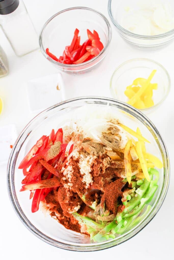Peppers and onions in a glass mixing bowl.