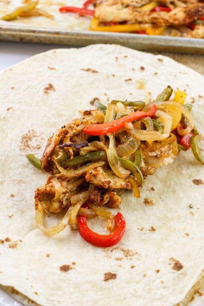 Meat and veggies being put in a tortilla.