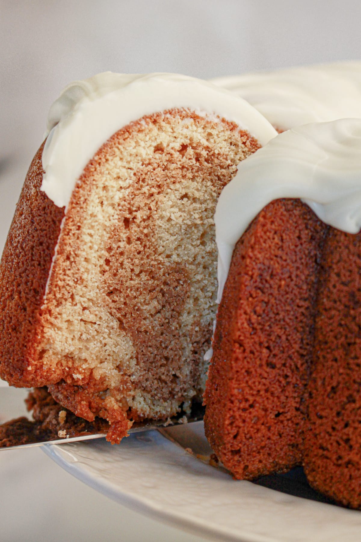 Slice of cinnamon roll bundt cake being removed from cake.